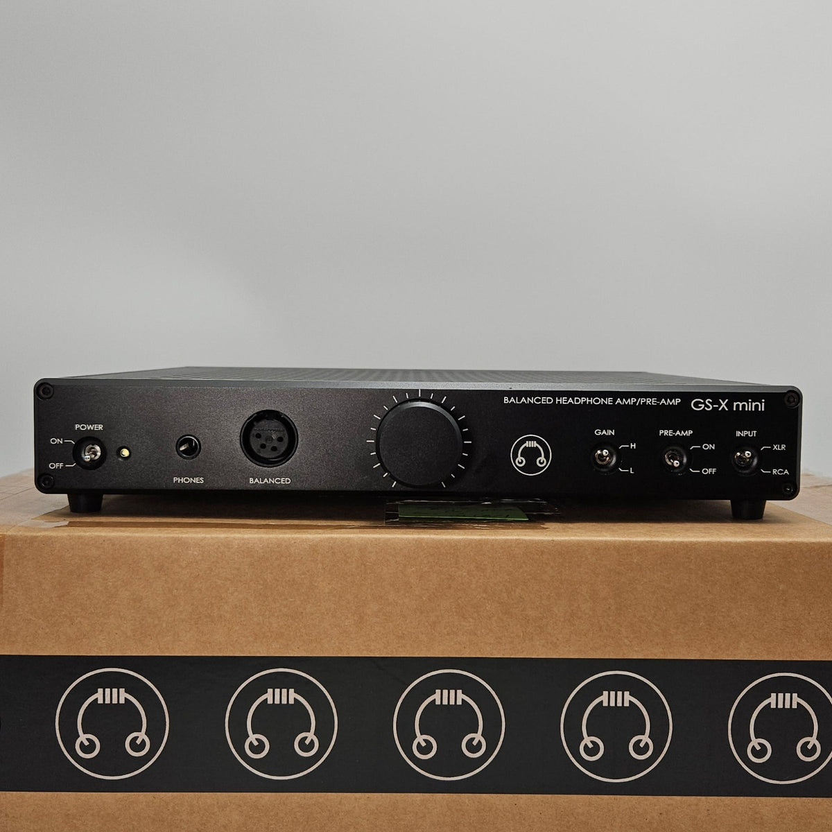 A black Audio-Technica ATH-M40x preamp module standing vertically next to its brown cardboard packaging box, which features the Audio-Technica logo printed on a black strip.